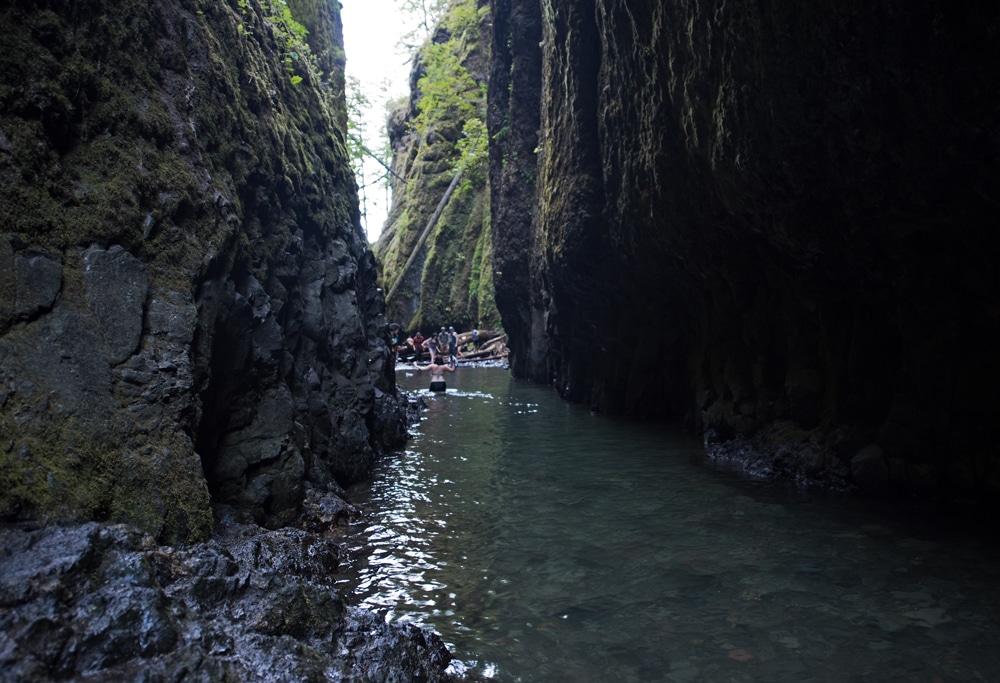 Brooke wading waist high through Oneonta Gorge headed towards lower oneonta falls