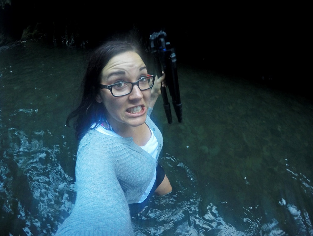 Brooke carrying a tripod as she walks through knee high water in the oneonta gorge