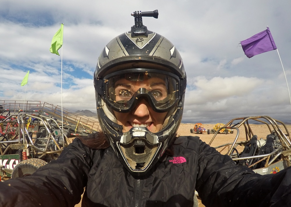 Brooke taking a selfie in a helmet and goggles with mud on them from our dune buggy chase outside the las vegas strip