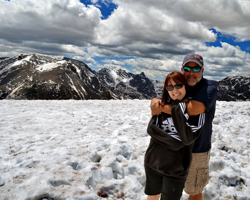 Brooke and her dad on trail ridge road 
 in colorado with snow on the ground and a beautiful blue sky