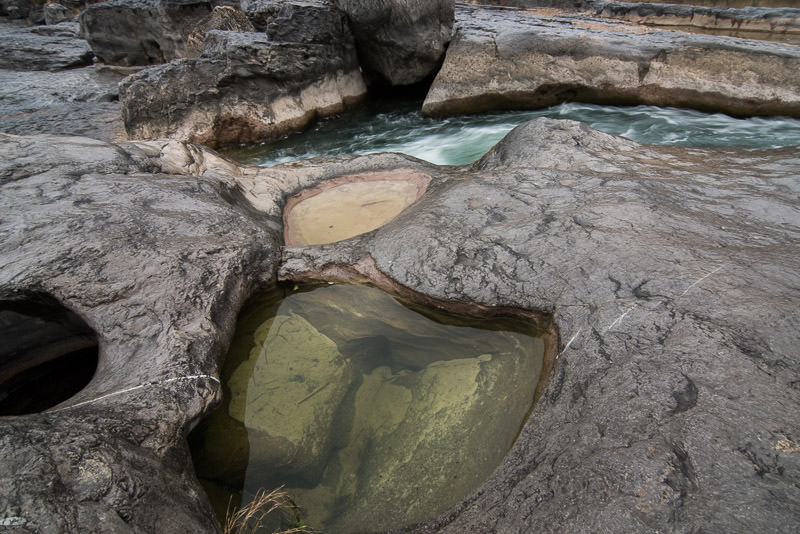Water flowing through a crack in the rocks with a pool of water in a small pocket in the limestone