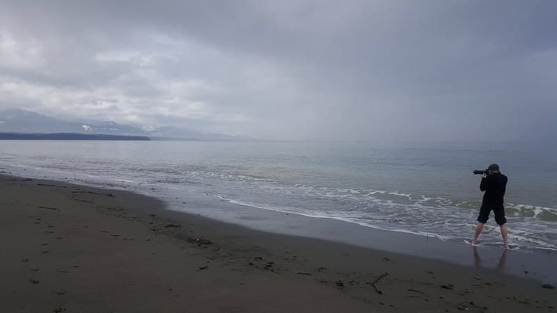 Buddy taking photos while standing in t he water at a beach