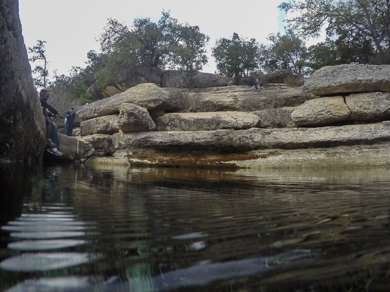 Visitor dangling his feet over the viewing platform of Jacob's well