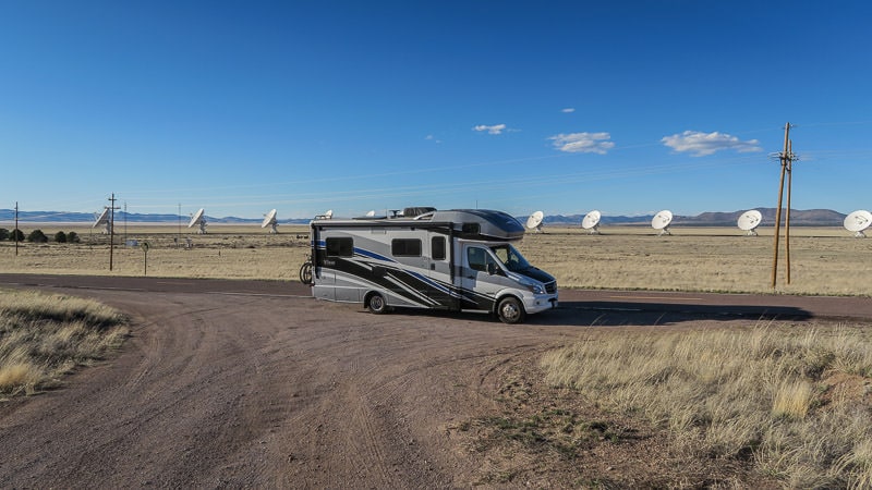 Winnebago View parked along the road with the satellites from the very large array in new mexico behind it