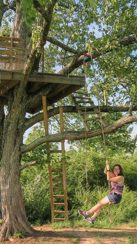 Brooke on a rope swing next to the treehouse
