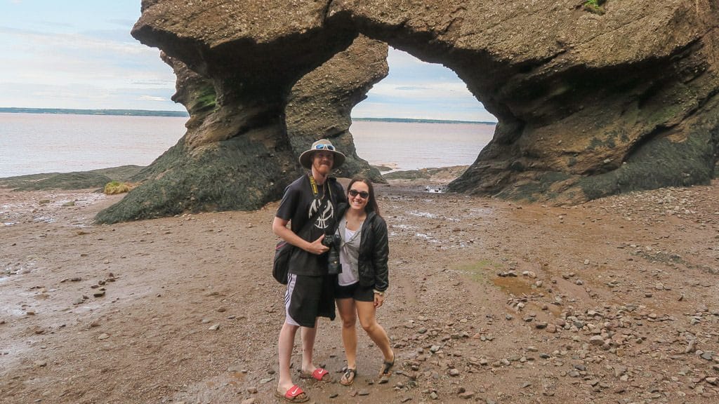 Brooke and Buddy with very muddy shoes and feet getting a picture near the arches rocks during low tide.