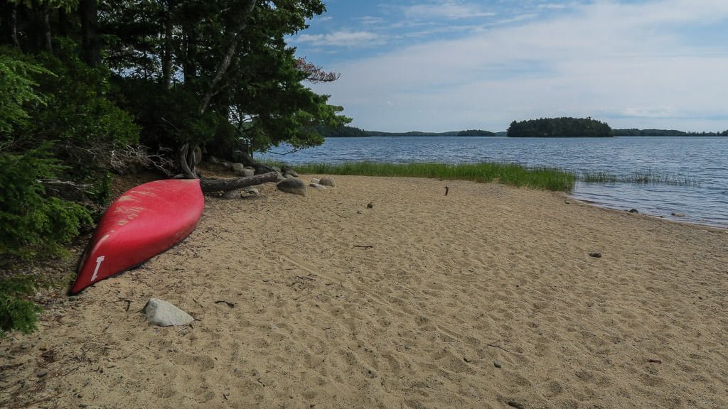 Canoe sitting in the sand at one of the beaches in kejimkujik national park and national historic site