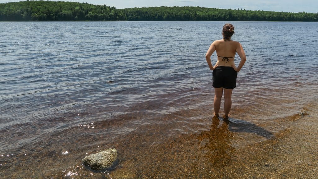 Brooke standing in the clear and calm water of a kejimkujik beach