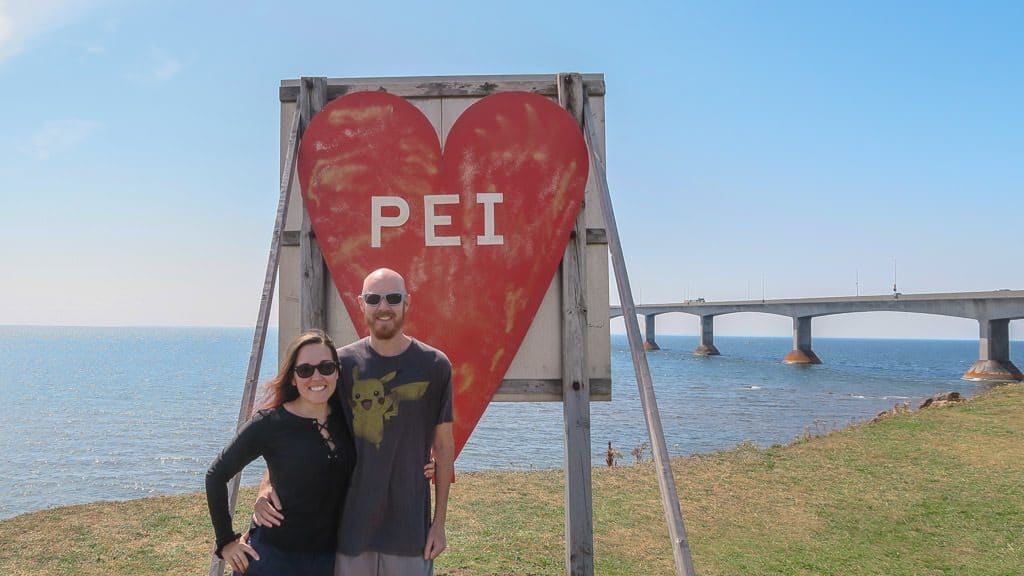 Brooke and Buddy taking a photo next to the PEI sign before crossing Confederation bridge to leave Prince Edward Island