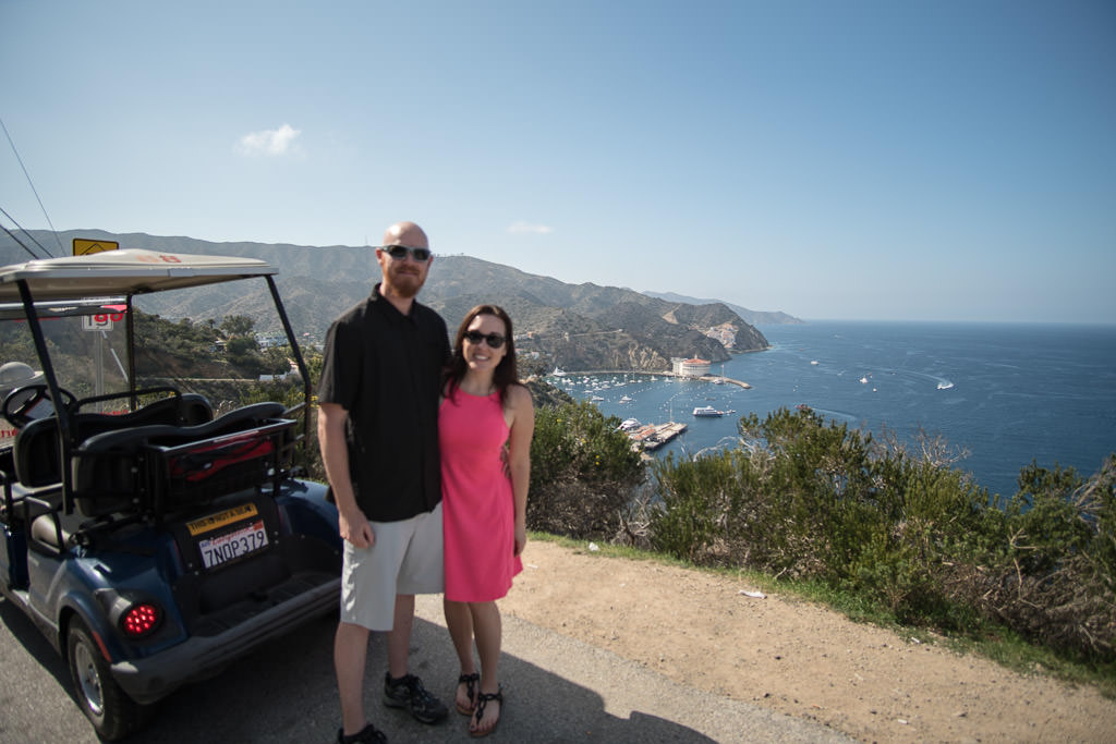 Brooke and Buddy posing next to their Catalina Island Golf Cart rental overlooking Avalon Harbor