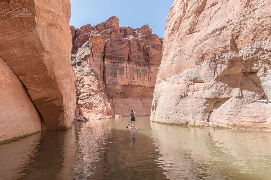 Brooke Paddleboarding on Lake Powell between giant rock cliffs on the way to Antelope Canyon in Page Arizona