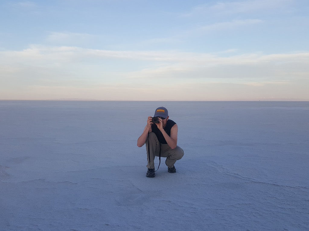 Buddy kneeling down and taking photos at the Bonneville Salt Flats during dusk
