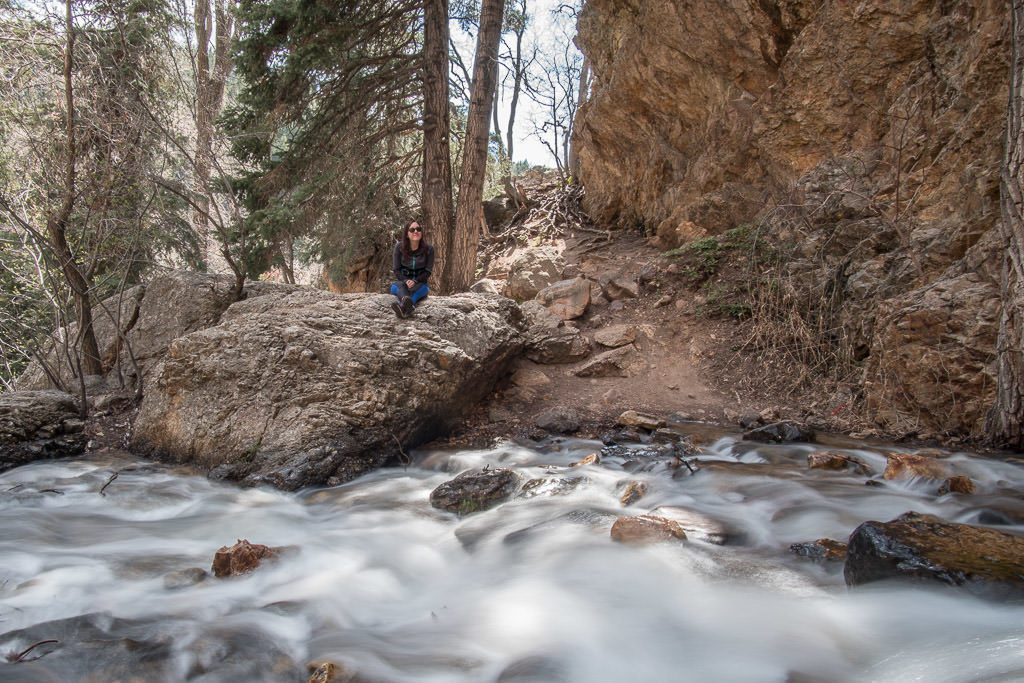 Brooke sitting atop a rock next to the river that flows from Hidden Falls