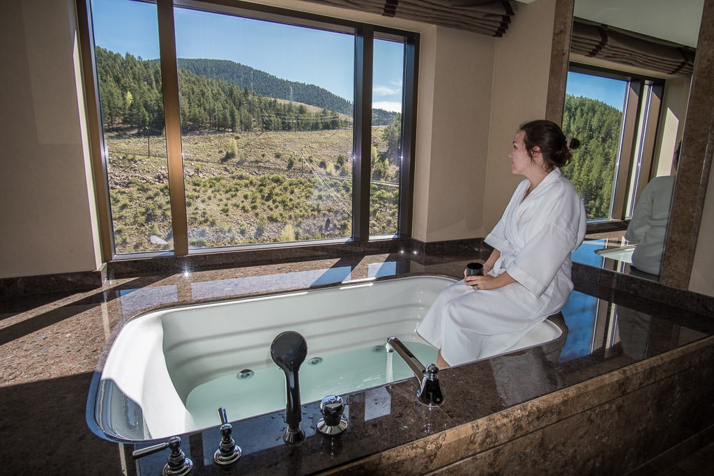 Brooke sitting on the edge of the very large jetted tub drinking her coffee looking out at our mountain views in our room at Ameristar Black Hawk Resort