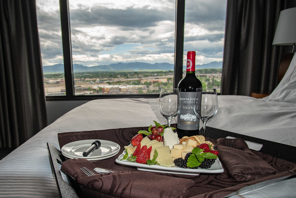 Cheese and fruit plate with a bottle of wine on our bed and a beautiful mountain scene out the large windows at the Westin Hotel in Westminster