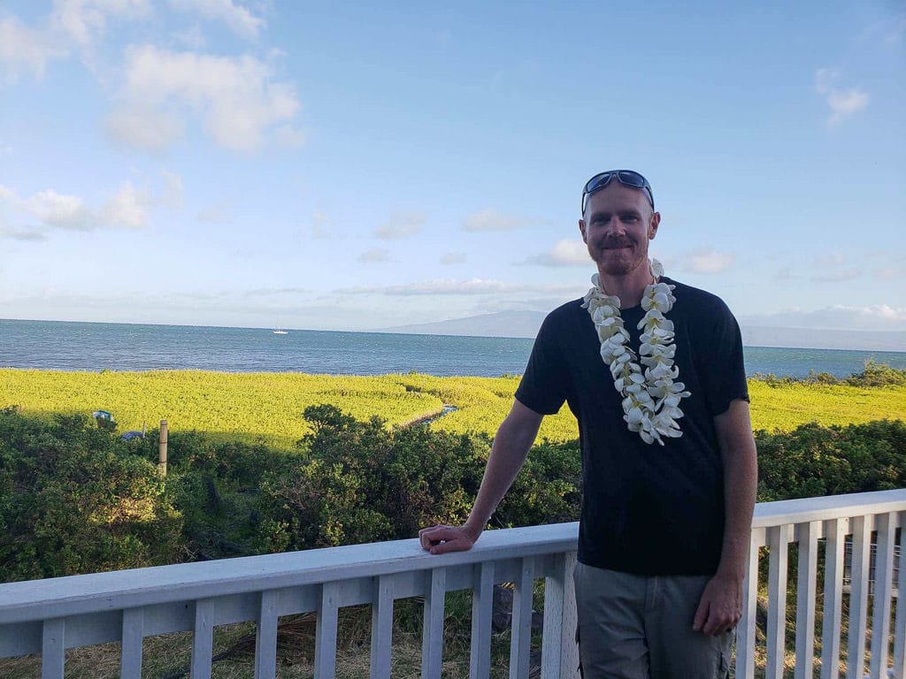 standing on porch at our house sit in molokai wearing a hand-made lei from homeowners