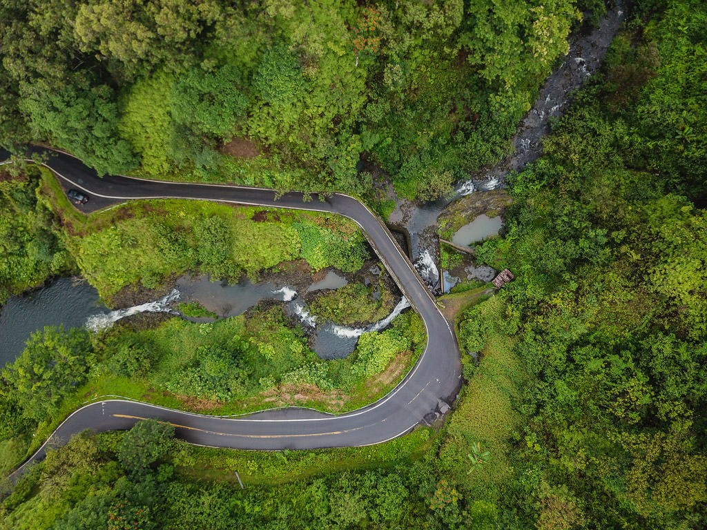 Aerial view of a curve on the Road to Hana with waterfalls on both sides of the road