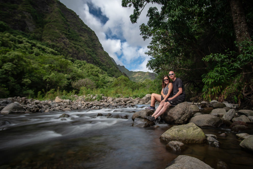 Brooke and Buddy sitting on a rock together next to the river in Iao Valley State Park