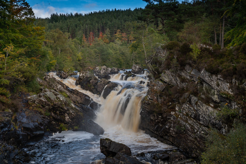 The powerful and large Rogie Falls with some trees in the background changing color with the autumn season