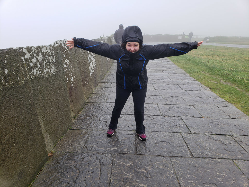 Brooke leaning into the wind during our windy, rainy and foggy adventure to the Cliffs of Moher