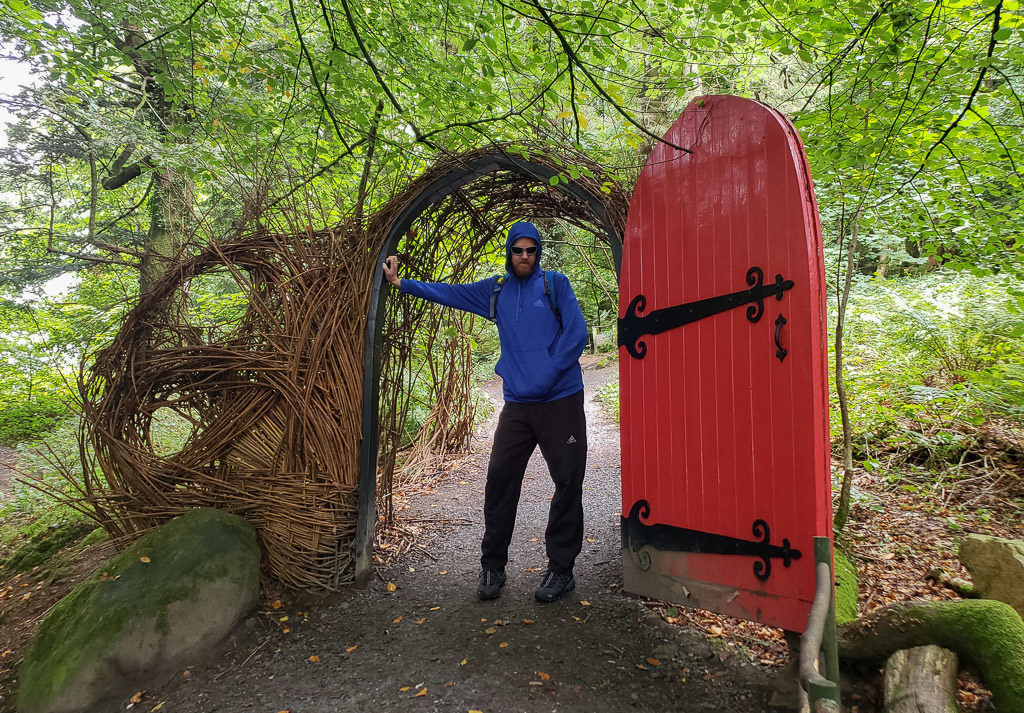 Buddy next to a giant red door that you walk through during part of the Giant's Lair Story Trail at Slieve Gullion Forest Park