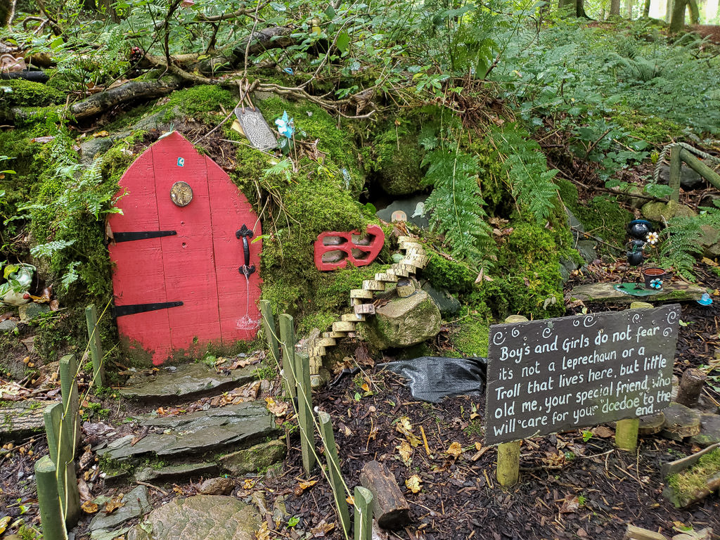 Small fiary village at the Giant's Lair with a sign that reads "Boys and Girls do not fear its not a Leprechaun or a Troll that lives here, but little old me, your special friend, who will care for your 'doedoe' to the end..." with pacifiers around it
