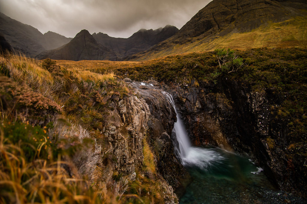 Waterfall with a dramatic mountainous scene behind it at Fairy Pools in Isle of Skye