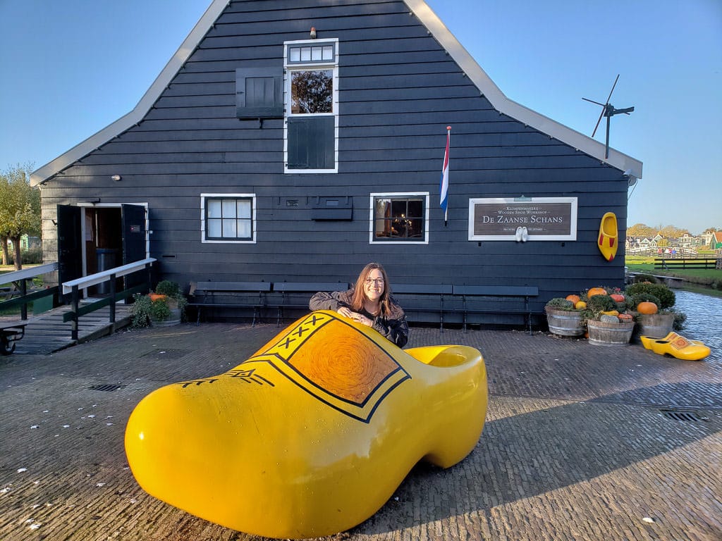 posing in a dutch wooden shoe during zaanse shans day trip from amsterdam to holland's countryside