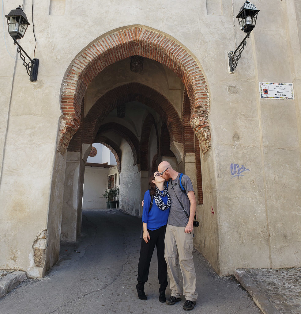kissing in front of medina arch in tangier on day trip to Morocco tour