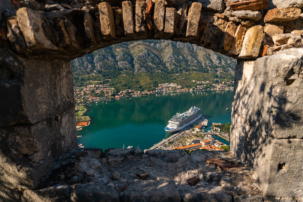 View from one of the Fortress windows looking out into Kotor Bay at a cruise ship that is docked for the day.