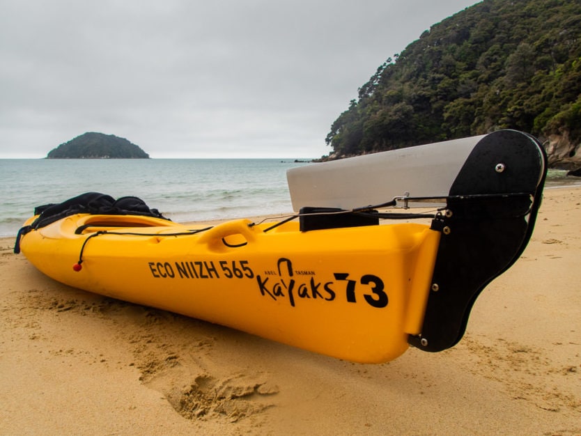 Abel Tasman Kayaks sea kayak on part of the Abel Tasman Coast Track near Onetahuti Bay with Tonga Island in the background
