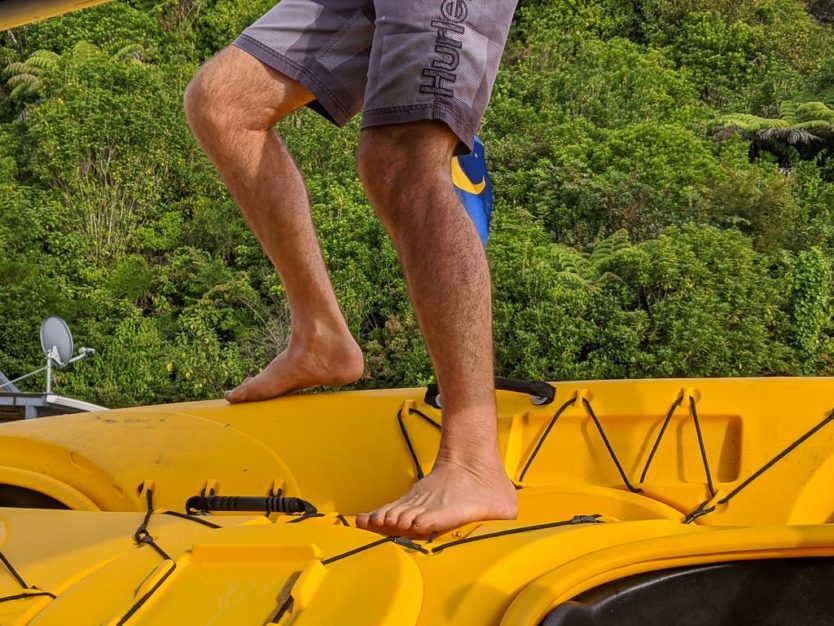 guy standing on kayaks as he stacks them on a boat for transport