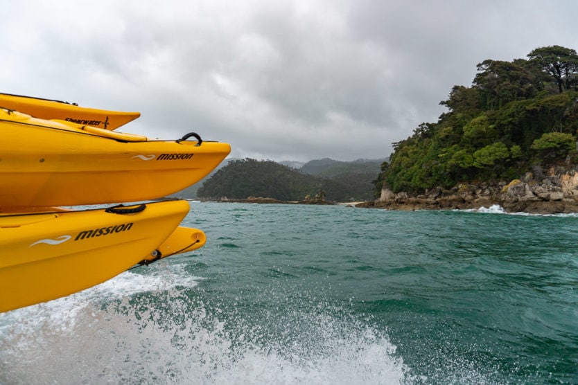 water splashing on sea kayaks while the abel tasman water taxis takes us to dropoff point